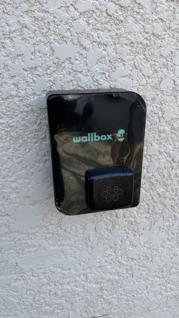 Borne de recharge Wallbox Pulsar noire installée sur une façade par Sanou Électricité