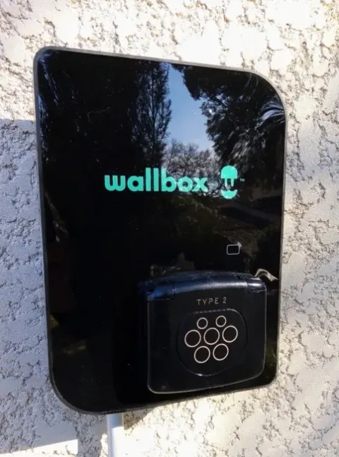 Borne de recharge Wallbox installée en extérieur sur un mur d'habitation